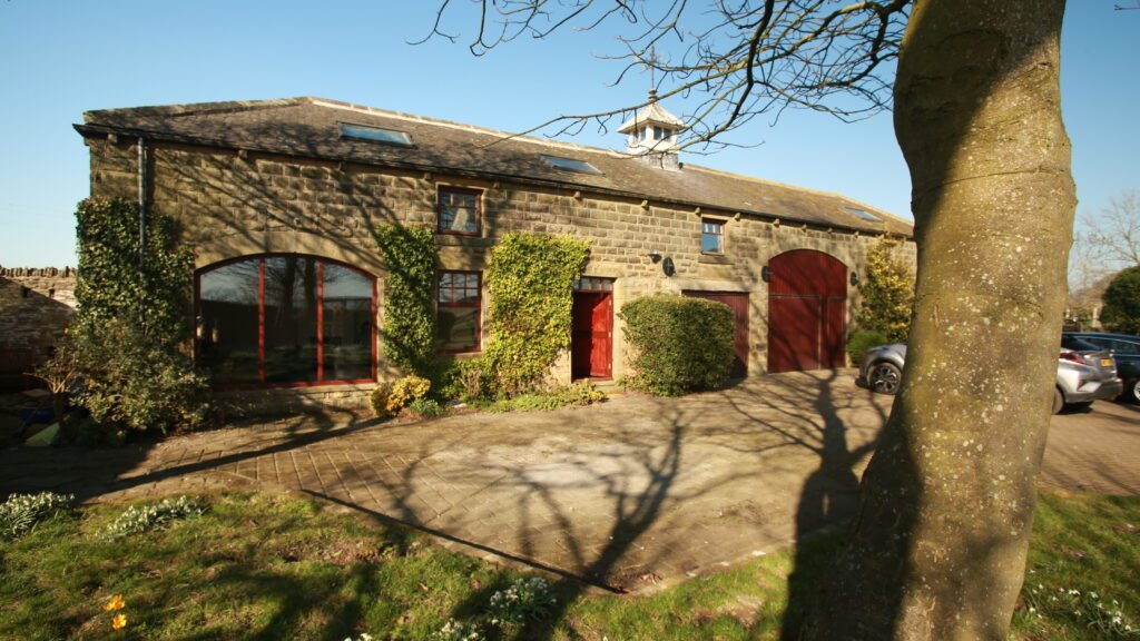 Copster Barn’s stone building and arched windows beneath a garden tree