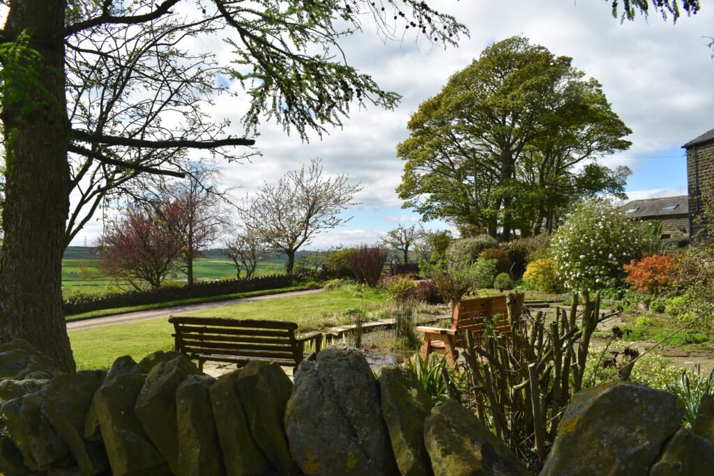 Garden seating among mature trees and dry-stone walls at Copster Barn