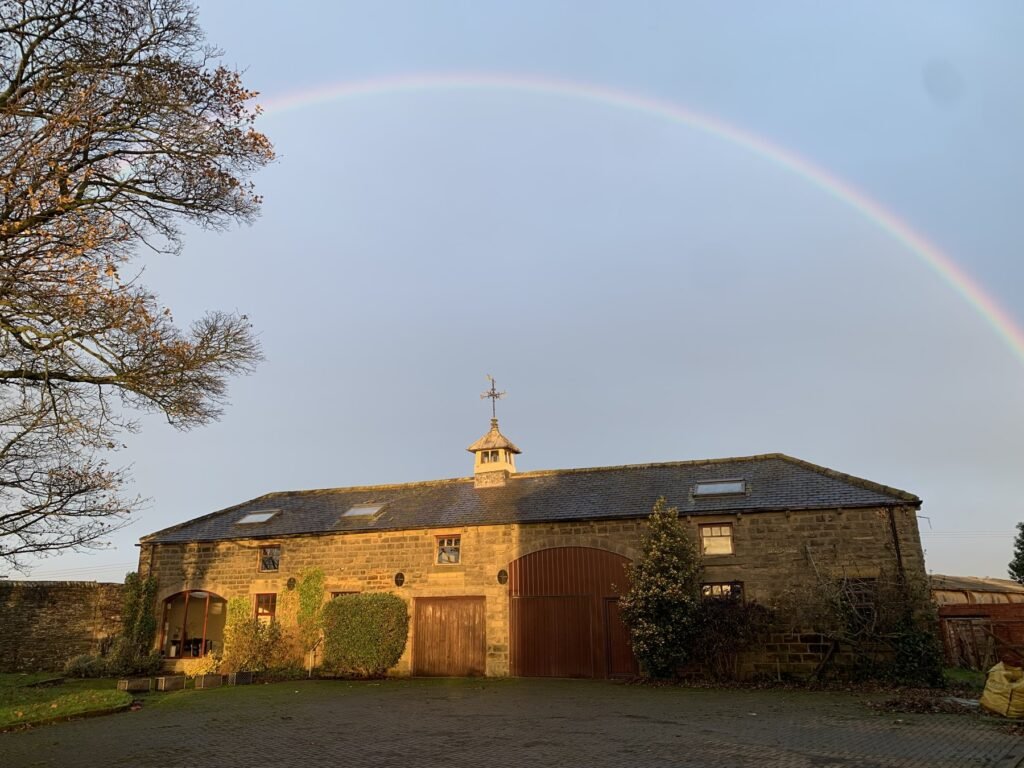A rainbow above Copster Barn in evening sunlight